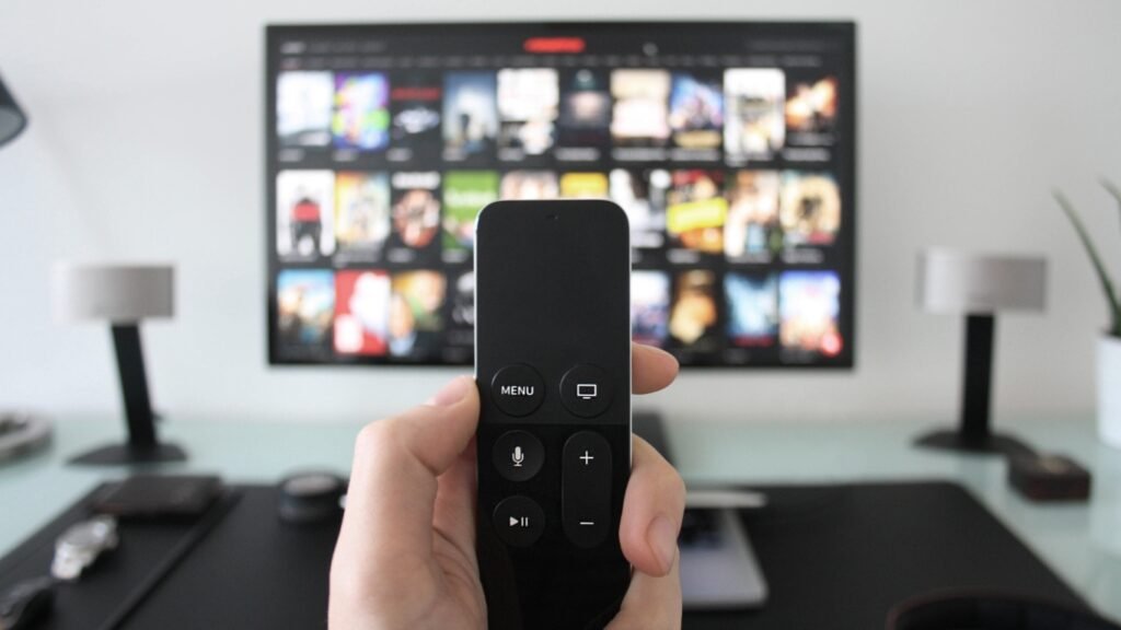 Hand holding remote in front of a TV screen